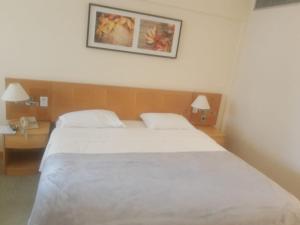 a bedroom with a large white bed and two lamps at Hotel Alphaville Apto 909 in Barueri +1 photo