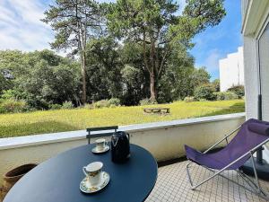 d'une table et de chaises sur un balcon avec vue sur un parc. dans l'établissement Studio lumineux proche plage, bois, marché - 4 pers, parking, animaux acceptés - FR-1-245-207, au Pouliguen 3 autres photos
