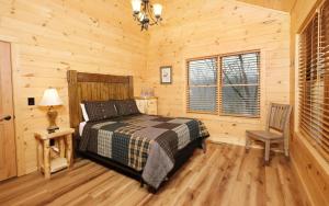 a bedroom with a bed and a chair in a log cabin at Hot tub and game room! - Black Bear Crossing in Gatlinburg