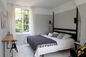 a white bedroom with a large bed and a window at La Maison & L'atelier in Neuilly-en-Thelle