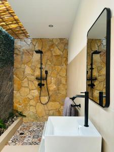 ein Badezimmer mit einem Waschbecken und einer Steinmauer in der Unterkunft Las Flores Lombok in Kuta Lombok