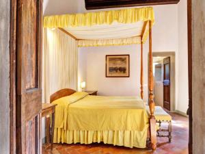 - une chambre avec un lit à baldaquin et un couvre-lit jaune dans l'établissement Villa Petra, à Greve in Chianti