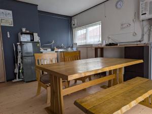 a kitchen with a wooden table and a table and chairs at 海辺の宿錦 b in Tomakomai