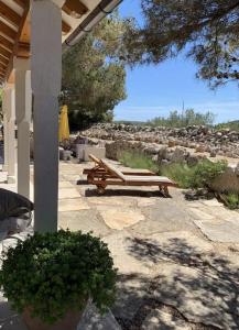 a patio with two wooden benches on a stone ground at Kuća za odmor Brigitaa in Jezera