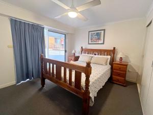 1 dormitorio con cama de madera y ventana en Ocean Shores Apartment 13, en South West Rocks 9 fotos más