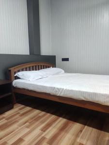 a bedroom with a bed with white sheets and a wooden floor at Vidhara Rooms in Trivandrum +18 photos