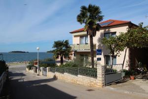 una casa con una palmera frente al agua en Rooms and Apartments Bella Vista, en Rovinj