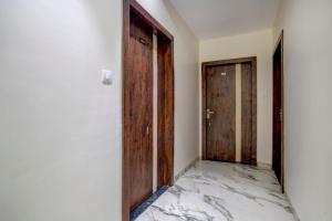 a corridor with two wooden doors and a marble floor at Capital O Abri Krishna in Indore