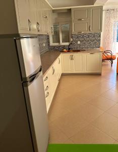 a kitchen with white cabinets and a refrigerator at Sunshine Guesthouse Dhermi in Dhërmi