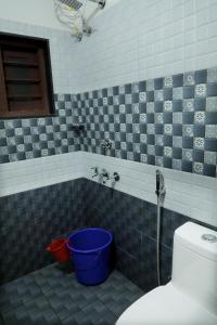 a bathroom with a toilet and a blue and white tiles at Bethel Homestay Thiruvallam in Trivandrum