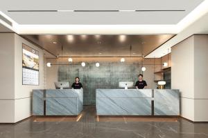 2 persone sedute alla reception in una hall di Atour Hotel Changsha South Station Guitang Metro Station a Changsha