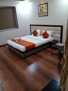 una camera da letto con un letto grande con cuscini arancioni di Hotel Raviraj Palace a Rajkot Altre 3 foto