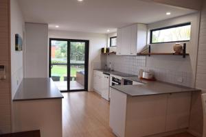 a kitchen with white cabinets and a counter top at Rockleigh - Bring your own linen. in South West Rocks