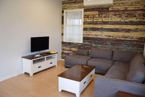 a living room with a couch and a flat screen tv at Rockleigh - Bring your own linen. in South West Rocks