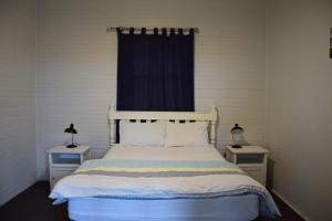 a bedroom with a white bed with two night stands at Rockleigh - Bring your own linen. in South West Rocks