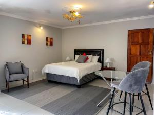 a bedroom with a bed and a table and chairs at Bobisemo Luxury Pretoria East Apartment in Tierpoort +26 photos