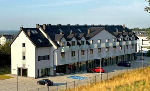 Un gran edificio blanco con coches aparcados en un estacionamiento. en Rent Apartment, en Wieliczka