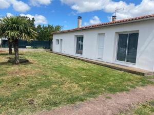 a white house with a palm tree in the yard at Maison Royan 9 personnes in Médis