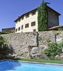 - un bâtiment au sommet d'un mur en pierre avec une piscine dans l'établissement Villa Petra, à Greve in Chianti