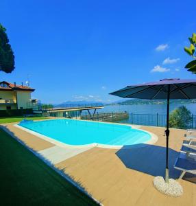 una grande piscina con ombrellone e sedie di Scarlet Flower - Lago Maggiore a Meina