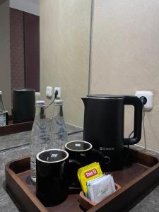eine Küchentheke mit Spüle mit Kaffeekanne und Flaschen in der Unterkunft Grand Arjuna Hotel in Bandung
