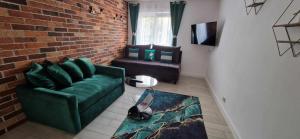salon z zieloną kanapą i ceglaną ścianą w obiekcie Apartamenty Orchidea Łeba w Łebie