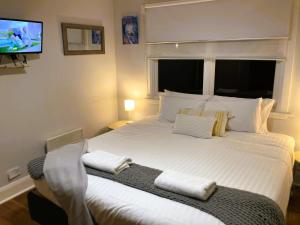 a bedroom with a large white bed with a television at Beach Holiday Home-Close to Airport-3 Bed & 2 Bath in Lauderdale
