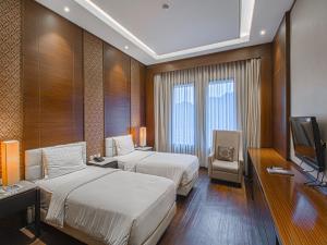 ein Hotelzimmer mit zwei Betten und einem Fernseher in der Unterkunft Grand Arjuna Hotel in Bandung