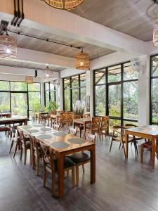 a restaurant with wooden tables and chairs and windows at TakFha Café & Resort in Ban Tha Ngam