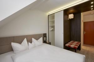 Un dormitorio con una cama blanca y una silla. en H+ Hotel Nürnberg, en Núremberg