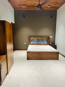 a bedroom with a wooden bed and a wall at Liyadi Addalaichenai in Addalachenai