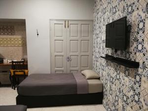 a bedroom with a bed and a tv on a wall at Check-Inn Guesthouse in Ipoh