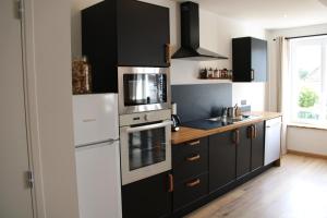 a kitchen with black cabinets and a white refrigerator at Appart Centre Village in Condette