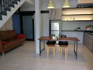 a kitchen with a table and two stools and a couch at Check-Inn Guesthouse in Ipoh