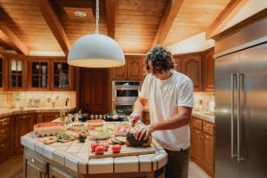 a man standing in a kitchen preparing food at Stone House by Casa Oso, hot tub, 43 private acres with hiking trails in Mariposa