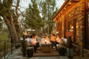 a group of people sitting around a table on a patio at Stone House by Casa Oso, hot tub, 43 private acres with hiking trails in Mariposa