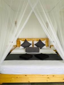 a bedroom with a white bed with black pillows at Idyll Cottage Ella in Ella +37 photos
