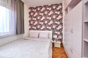 a bedroom with a bed with a floral wall at Апартамент Бриз in Burgas +34 photos