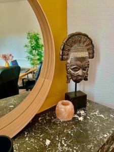a mirror and a statue of a mask on a table at L 'experience Unique in Rennes
