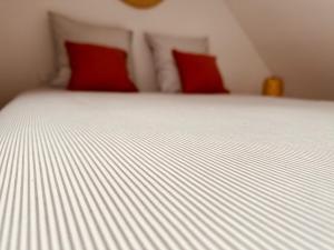 a white bed with red pillows in a bedroom at L 'experience Unique in Rennes