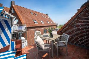 Un patio con una mesa y sillas en un balcón. en Residenz am Meer 24C Freissle, en Juist