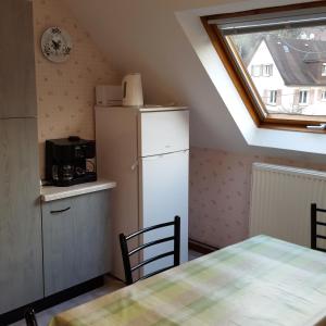 een keuken met een koelkast, een tafel en een raam bij Locations Dupertuis Alsace in Le Hohwald