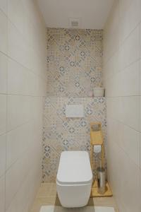 a bathroom with a white toilet and a tile wall at Apartmán Tatry Lesná in Nová Lesná +30 photos
