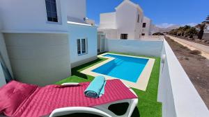 a backyard with a pool and a chaise lounge next to a house at Villa Esmeralda in Tías