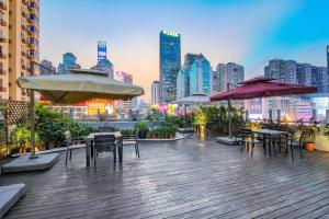 un patio all'ultimo piano con tavoli, sedie e ombrelloni di 趣创酒店 a Shenzhen