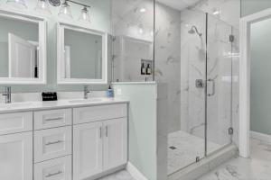 a white bathroom with a shower and a sink at Seaside Serenity Beautiful Home on Topsail 7 BR in Surf City