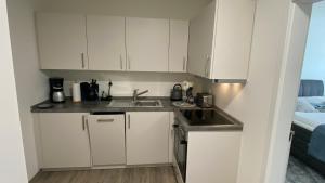 a small kitchen with white cabinets and a sink at Haus am Hafen Friedrichskoog App1 Hindenburg in Friedrichskoog