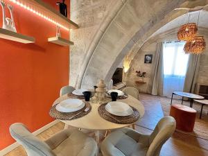 a dining room with a table and chairs and an orange wall at Joli appartement voûté dans le centre ville in Avignon