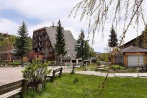 a park with benches and a building and trees at L'étoile des neiges Studio confort pour 4 personnes in Montclar