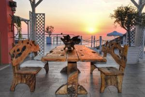 a wooden table and chairs with the sunset in the background at Petani Bay Hotel - Adults Only in Vóvikes